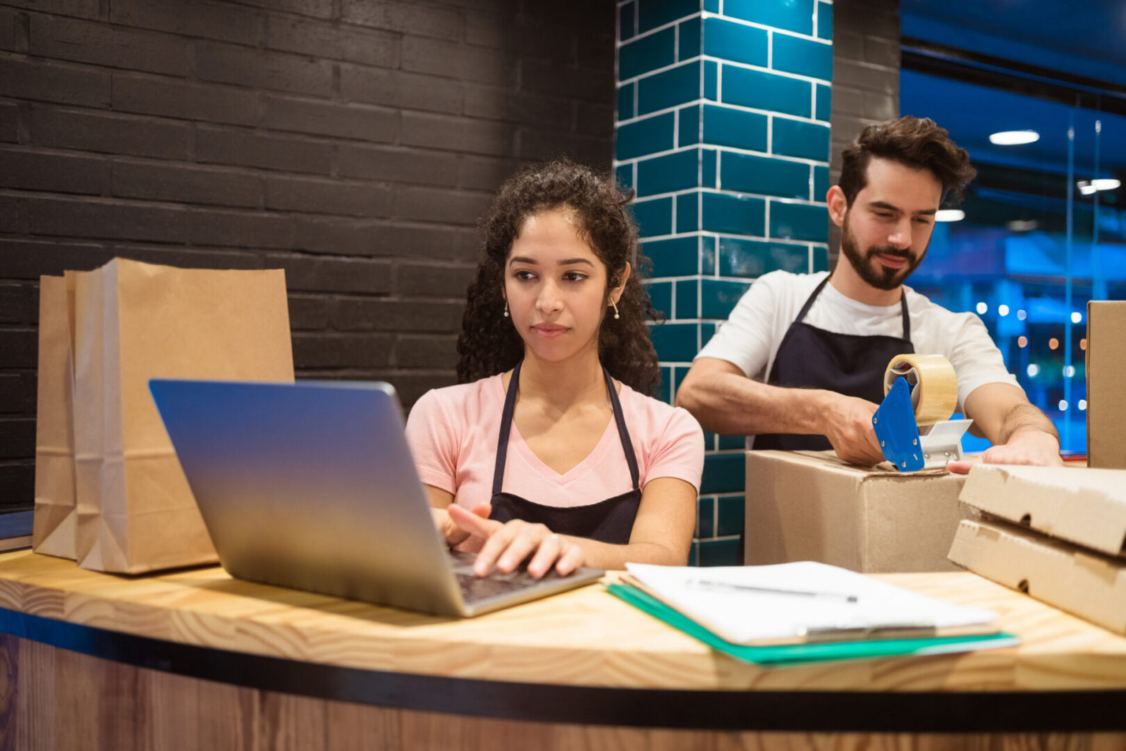 Workers packaging orders at a restaurant counter.