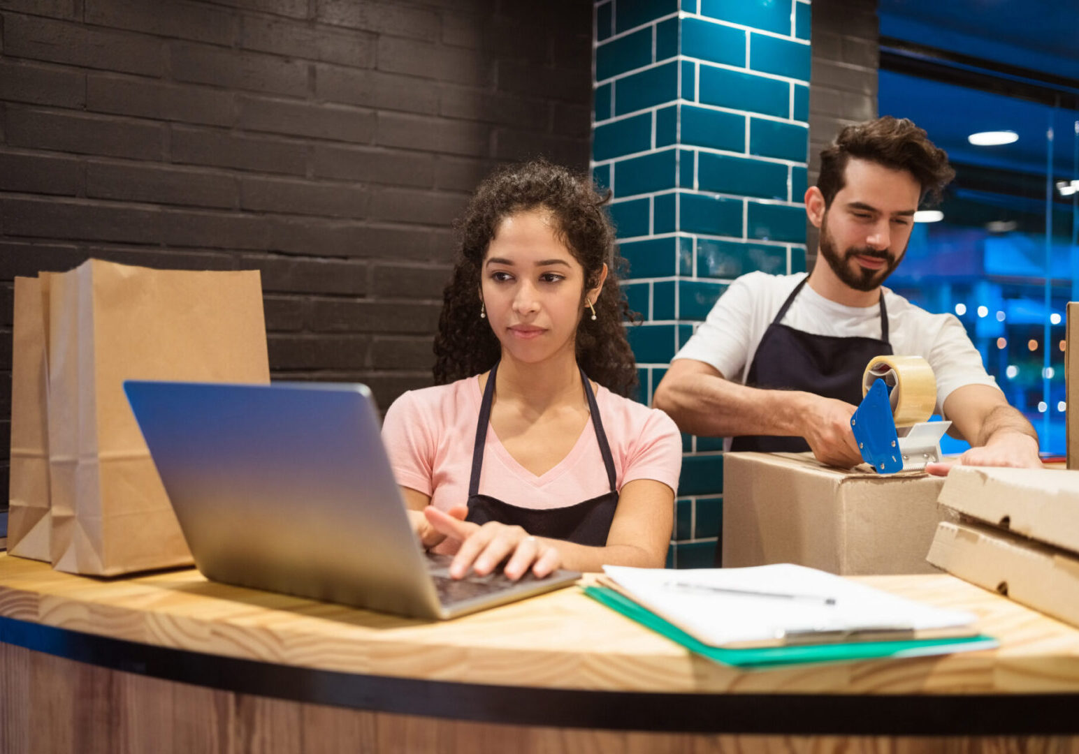 Workers packaging orders at a restaurant counter.